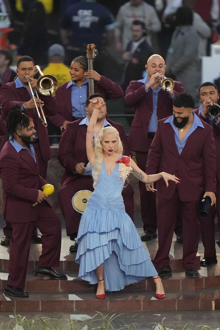 Lady Gaga performs onstage, dancing in a blue dress alongside live musicians during her guest appearance in the halftime show.