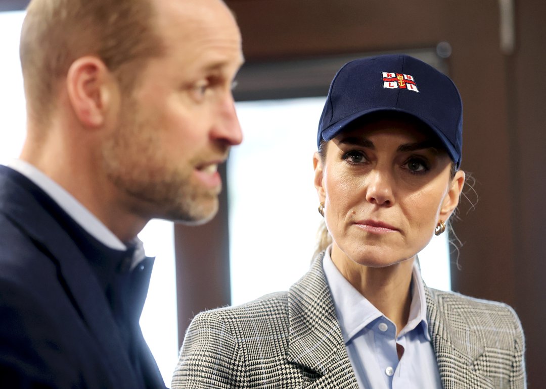 The Princess of Wales listens intently, her gaze fixed on the Prince of Wales mid-conversation, during their visit to the RNLI Tower Station on 12 March 2026 &mdash; a navy RNLI cap now replacing the grey blazer's more polished earlier look from the brewery. The couple were there to hear first-hand about the life-saving work carried out by staff and volunteers on the River Thames.