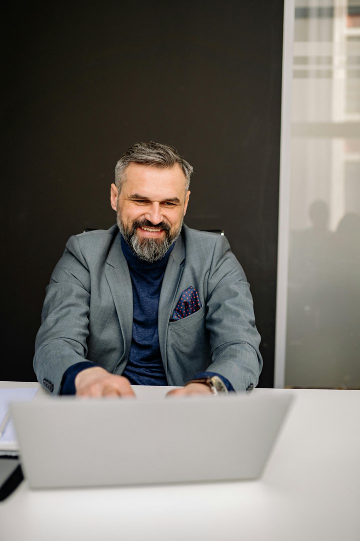 A happy man sitting behind a desk | Source: Pexels