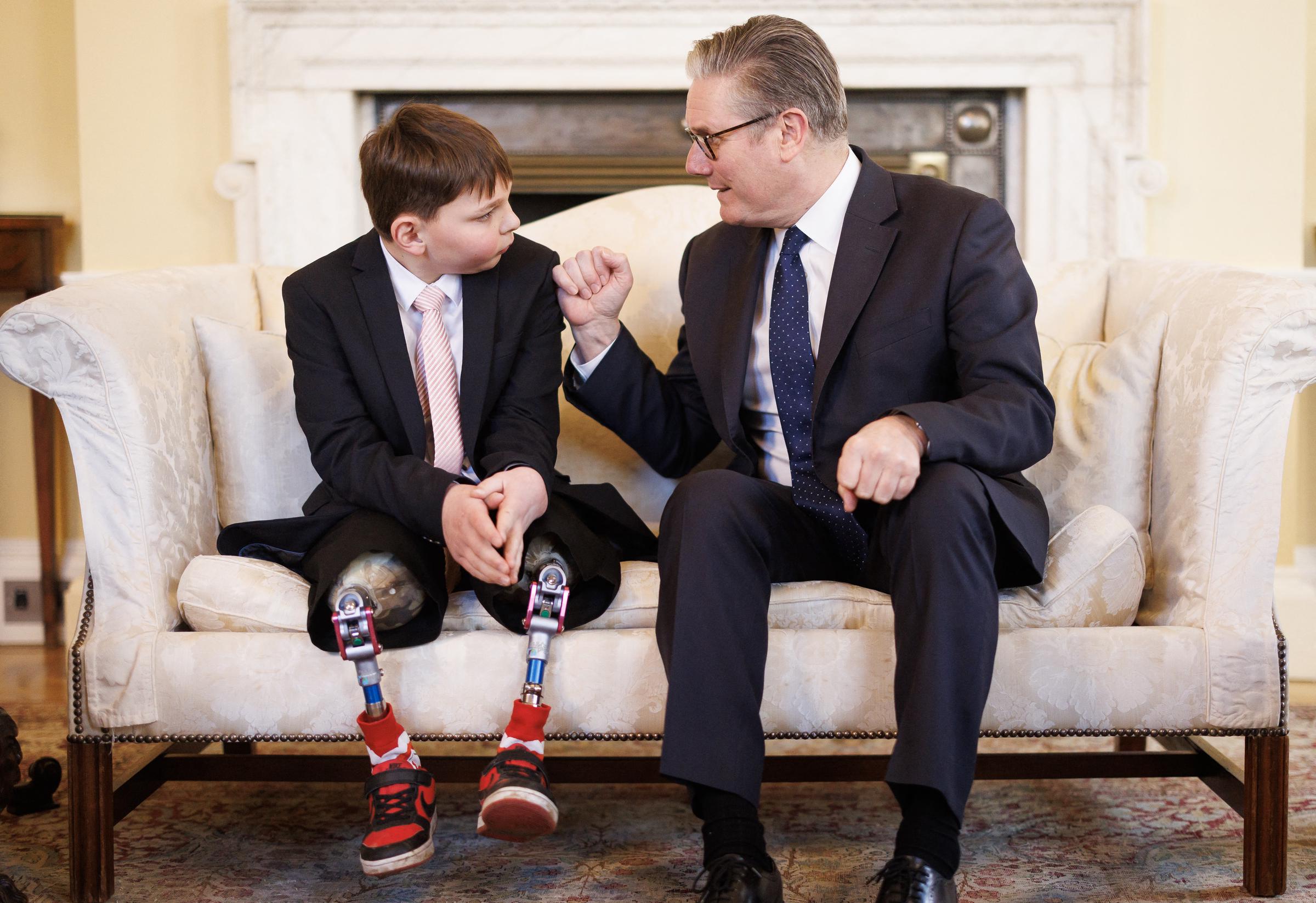 Tony and Prime Minister Starmer share a warm fist bump on the sofa, both leaning in towards each other with broad smiles. The moment captured a rare lightness during what was otherwise a deeply meaningful visit.