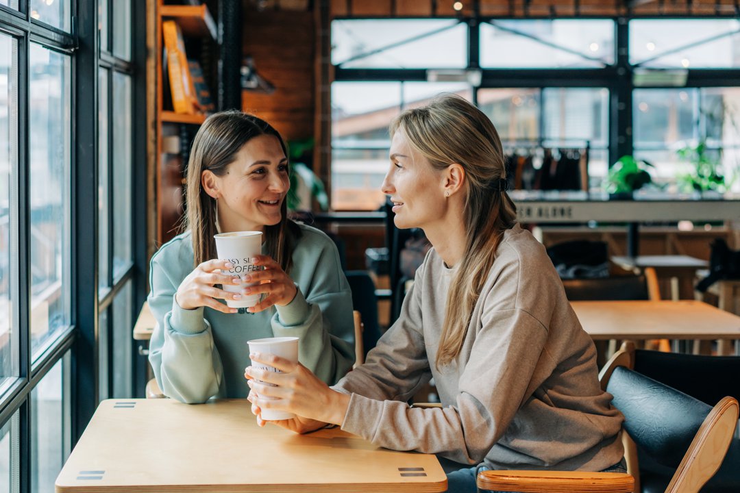 Two women sitting in a coffee house talking and drinking coffee | Source: Getty Images