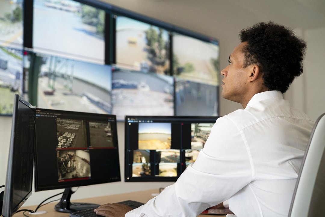 Young adult male security worker watching video wall while sitting at desk | Source: Getty Images