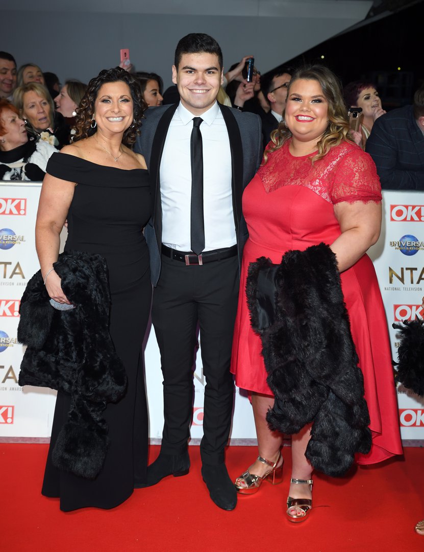 Tapper, in a red lace cap-sleeve dress and gold strappy heels, arrives with her mother Nikki — in an off-shoulder black gown — and her suited brother Josh on the NTA red carpet at The O2 Arena, London, January 2020. All three are grinning broadly as fans and photographers crowd behind them.