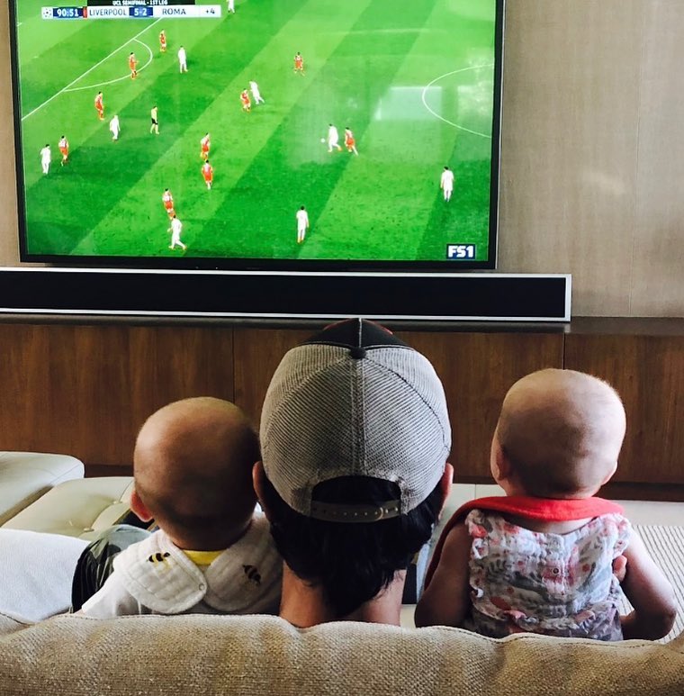 Enrique Iglesias holding Nicholas and Lucy Iglesias on a couch while watching a soccer game, from a post dated April 24, 2018 | Source: Instagram/enriqueiglesias
