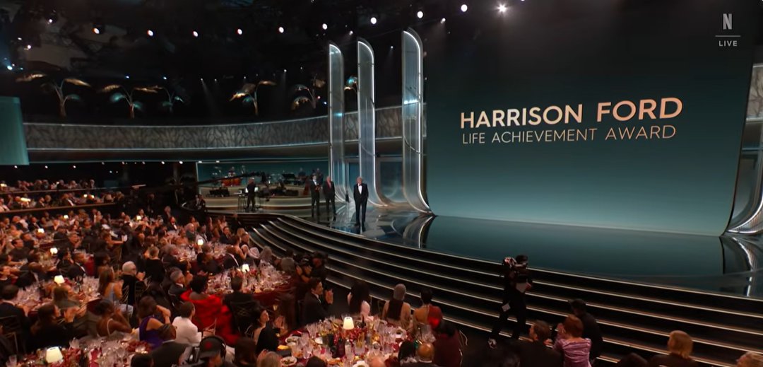 A wide view of the ceremony hall shows the stage illuminated as Harrison Ford is honored with the Life Achievement Award.. | Source: YouTube/Netflix
