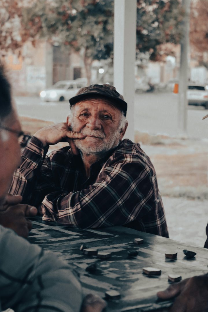Elderly man sitting at a table | Source: Unsplash