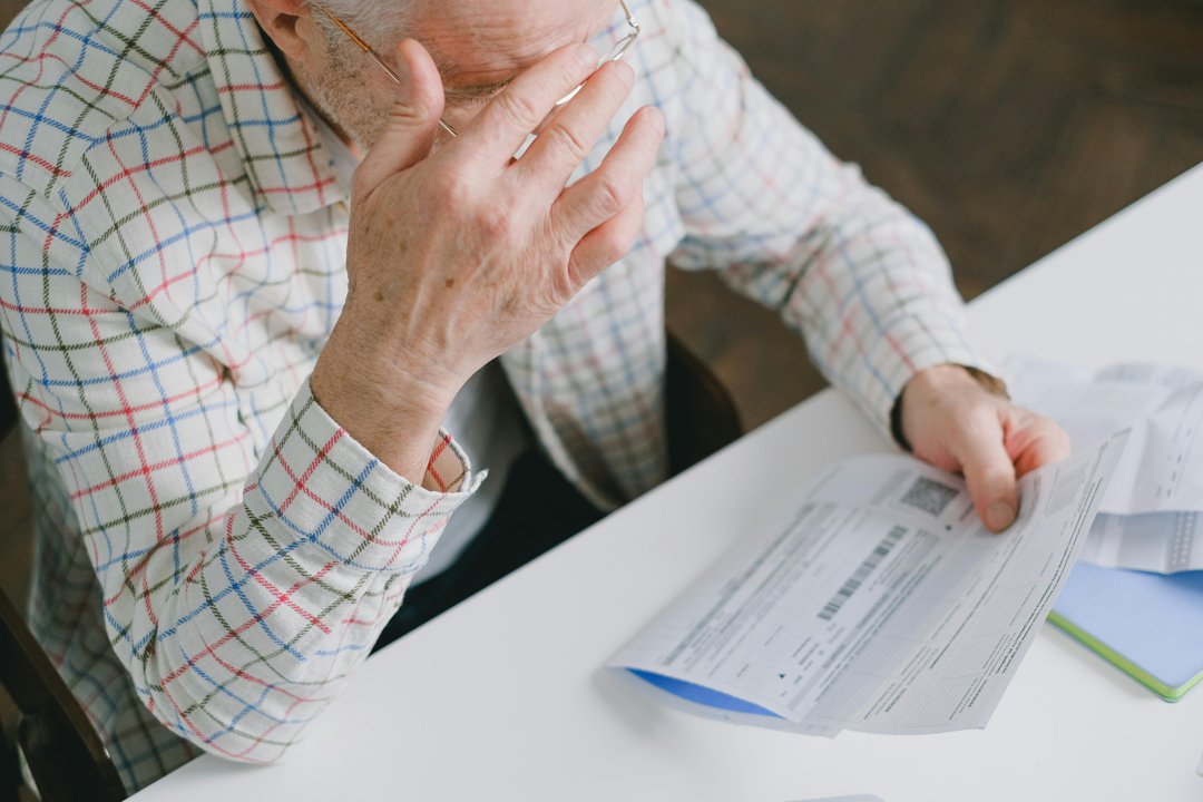Elderly man holding a piece of paper | Source: Pexels