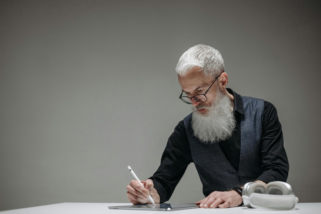 Bearded man using a light pen on a tablet | Source: Pexels