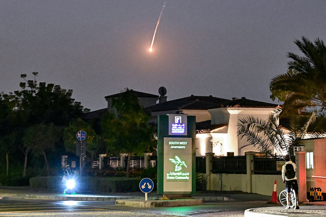 A cyclist watches as a projectile falls over Dubai on 28 February 2026. | Source: Getty Images