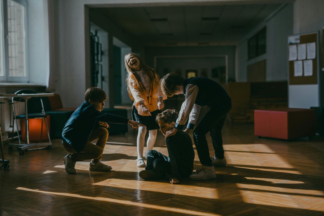 A group of children point and laugh at a seated classmate, capturing a moment of peer intimidation in a school setting. | Source: Pexels