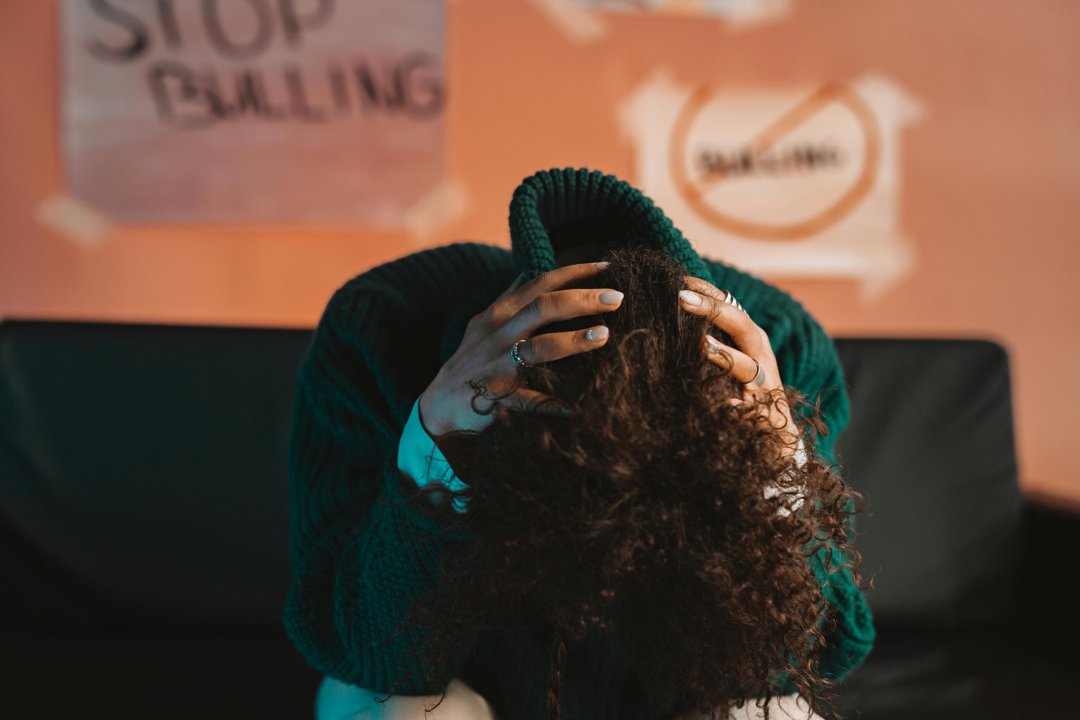 A student sits with their head in their hands beneath a