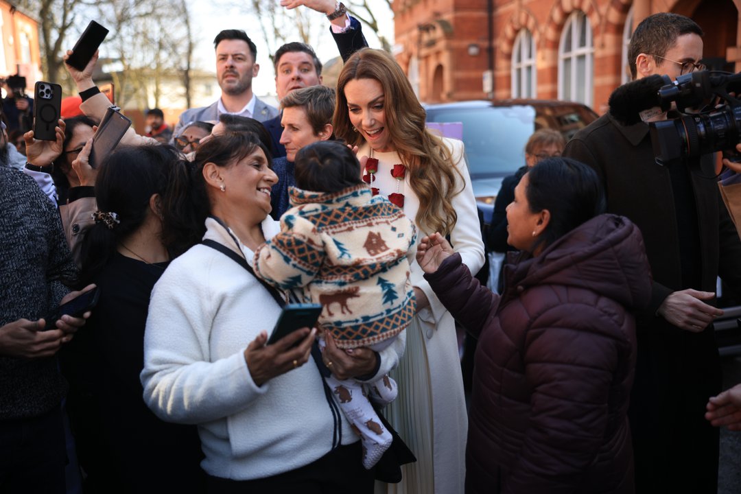 Catherine, Princess of Wales, greets well-wishers gathered outside after visiting the Aakash Odedra Company in Leicester, England, on March 5, 2026. Smiling warmly as she leans toward a child being held by a member of the crowd, the Princess of Wales pauses to chat and share a light-hearted moment during the lively walkabout.