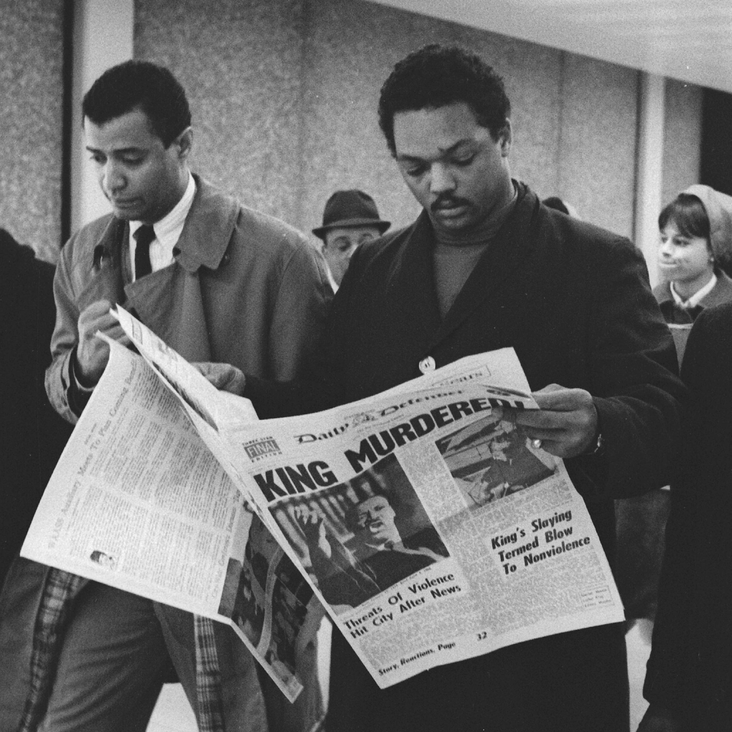 Jesse Jackson holds a copy of the Daily Defender newspaper, which features the headline 