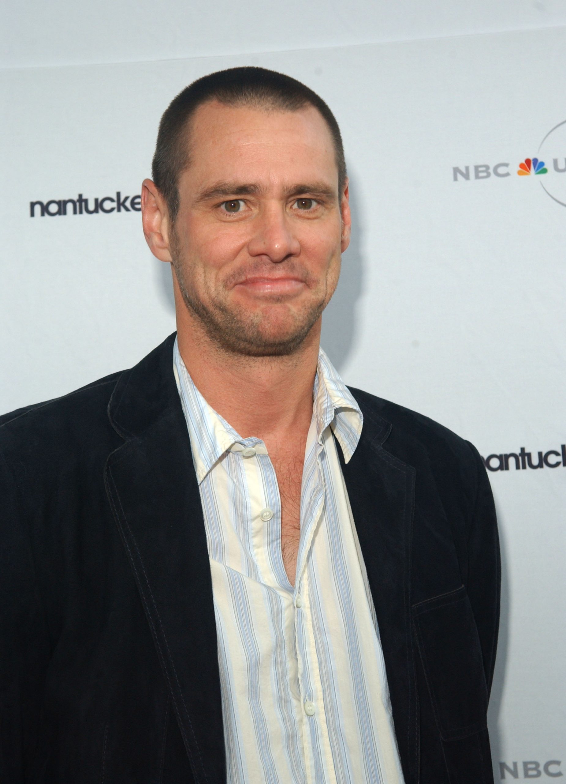 Sporting a close-cropped buzz cut, Jim Carrey flashes a funny smile in a striped open-collar shirt layered beneath a dark velvet blazer. The relaxed look adds a touch of understated ease to the Nantucket Film Festival&rsquo;s NBC Screenwriters&rsquo; Tribute to Charlie Kaufman.