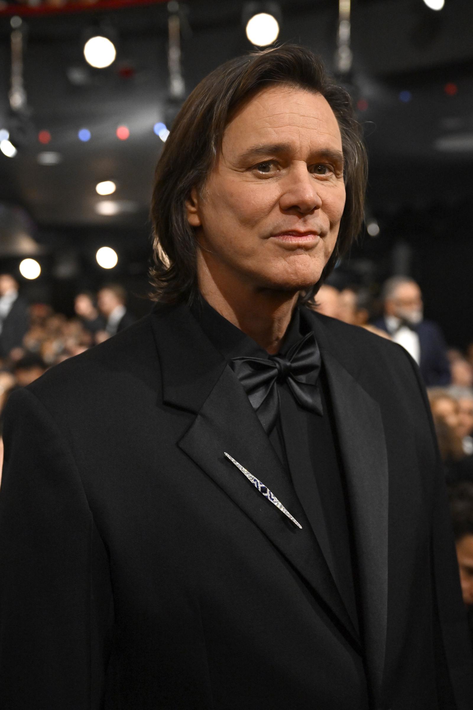 Dressed in a sharp black tuxedo with a satin bow tie, Jim Carrey exudes understated elegance. A sleek lapel pin adds a subtle gleam against the monochrome ensemble as soft stage lights glow behind him. He attends the 51st C&eacute;sar Film Awards at L'Olympia in Paris, France.