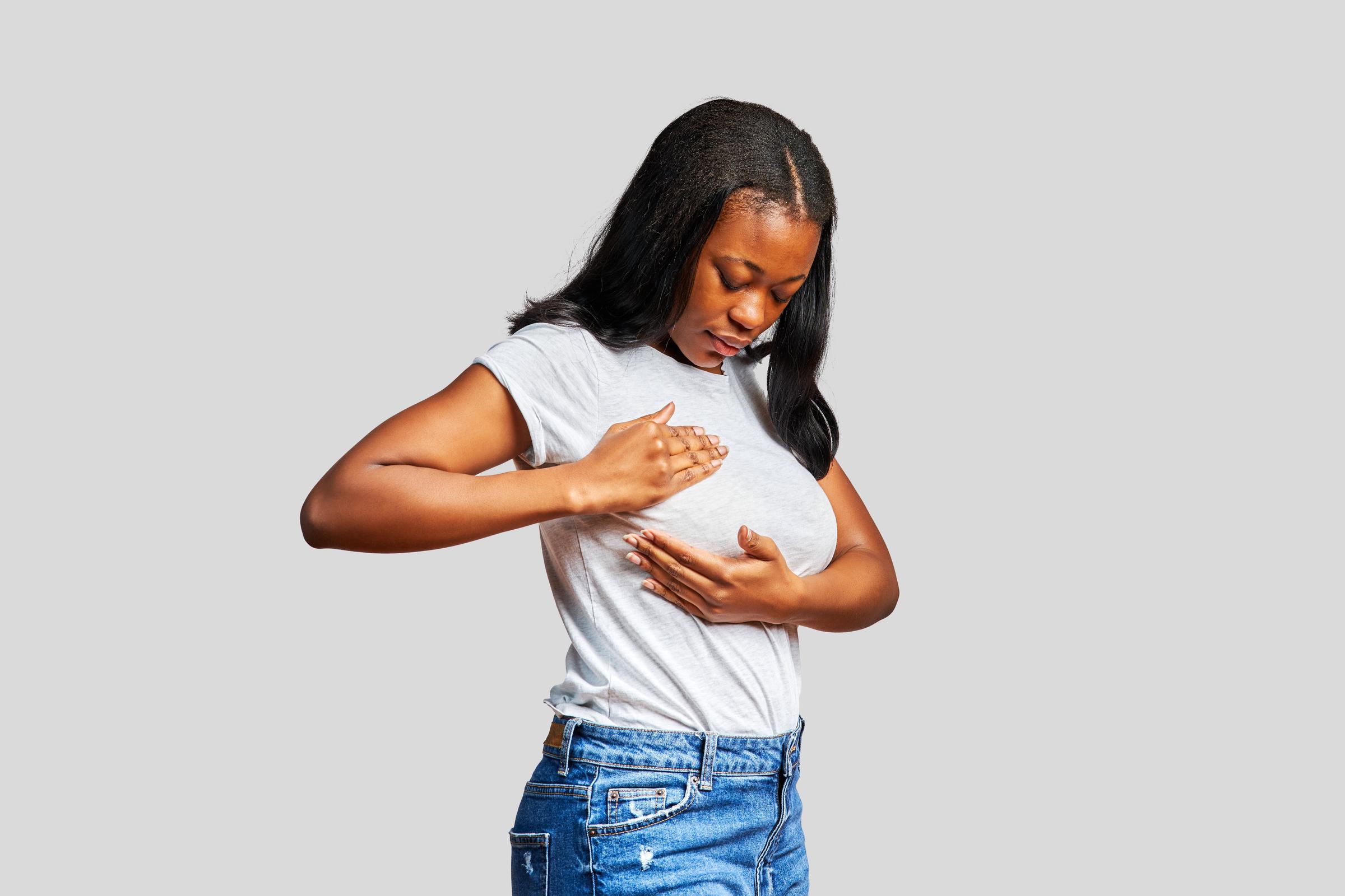 A young woman touching her breast in a cancer detection examination | Source: Getty Images