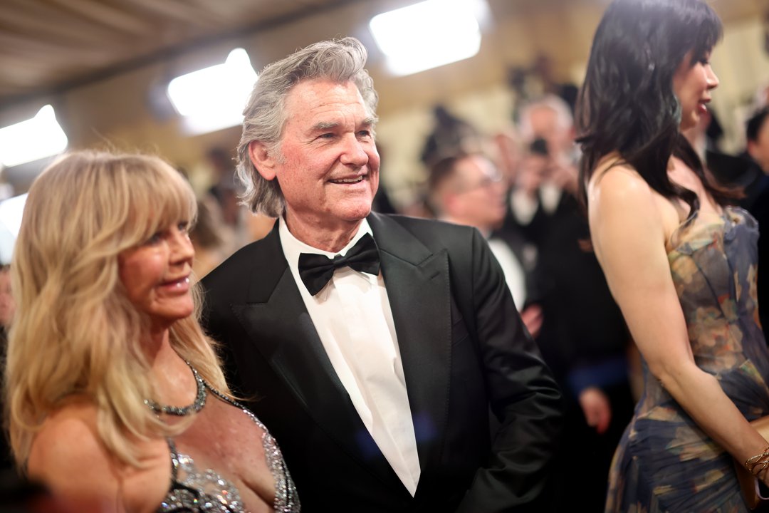 Goldie Hawn and Kurt Russell share a red carpet moment at the Oscars, with Russell in a classic black tuxedo as the longtime couple moves through the crowd of photographers and guests.