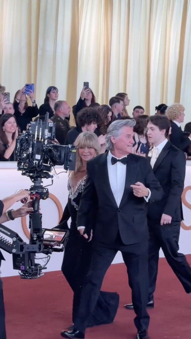 Goldie Hawn smiles while walking alongside Kurt Russell as the couple moves through the crowd, with guests and photographers watching from the sidelines. | Source: Instagram/enews