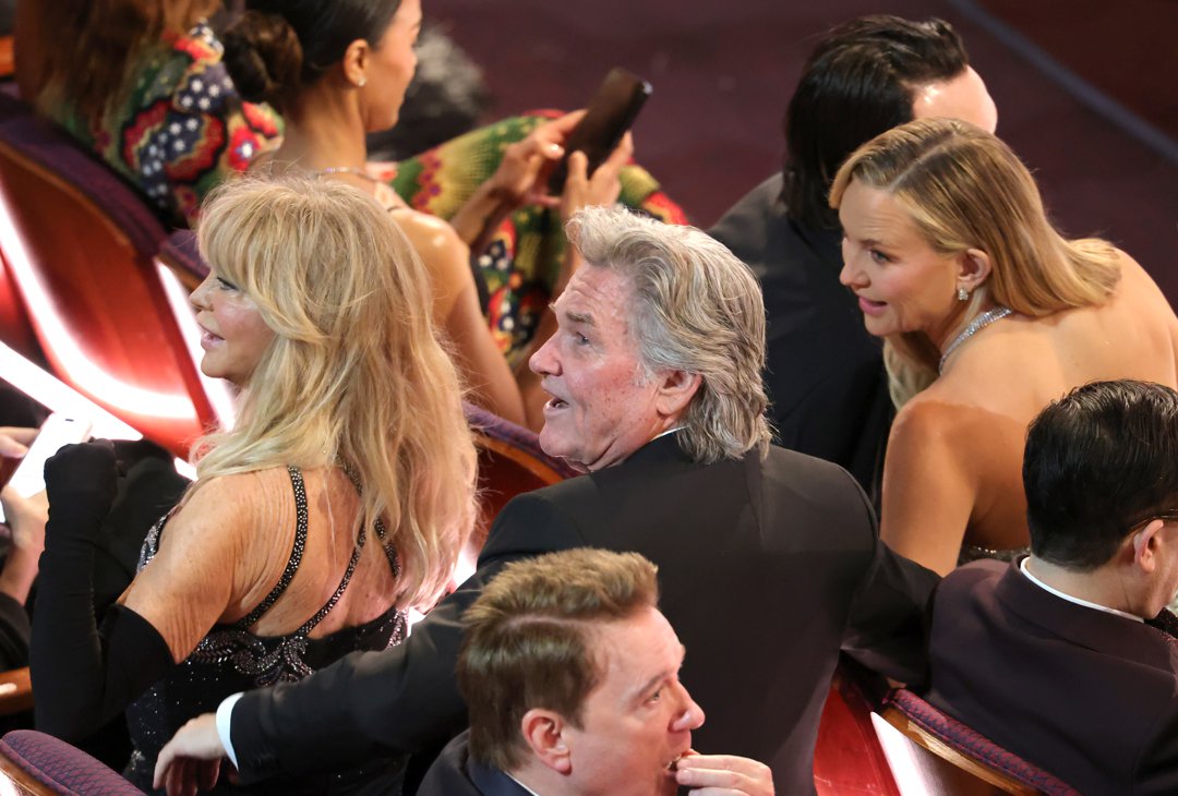 Goldie Hawn, Kurt Russell, and Kate Hudson share a moment from their seats during the ceremony, leaning toward each other while watching the show unfold.