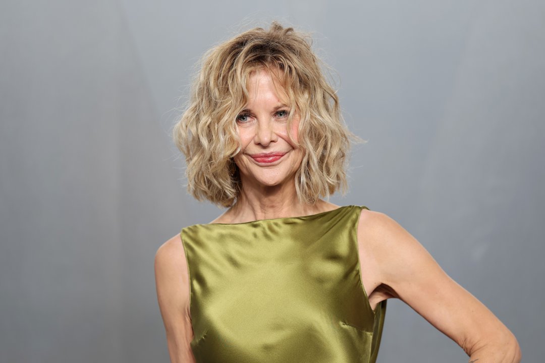 Meg Ryan poses for photographers with a soft, confident smile, presenting a refined red-carpet look as she arrives at the star-studded Vanity Fair Oscar Party.