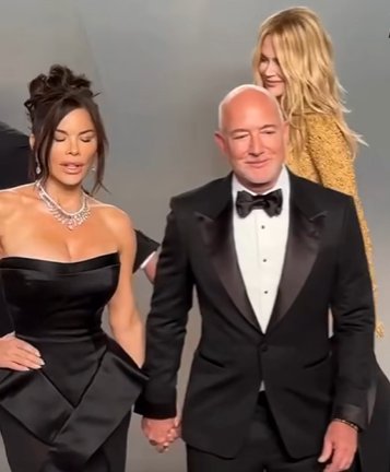 As Nicole Kidman passes behind them, Lauren S&aacute;nchez and Jeff Bezos remain hand-in-hand facing the cameras. | Source: Facebook/NewYorkPost