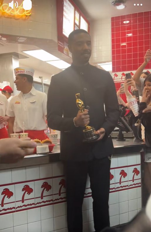 Michael B. Jordan stands inside In-N-Out Burger holding his Oscar as employees work behind the counter and fans nearby lift their phones to take photos. | Source: TikTok/donovanfilmz