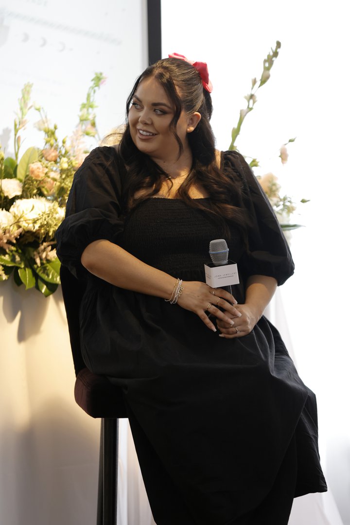 Moffatt spoke at Joma Jewellery's Mother's Day collection launch in London, seated with a branded microphone in hand, wearing an all-black dress with a smocked square neckline and wide puffed sleeves, her dark hair swept back with a red bow.
